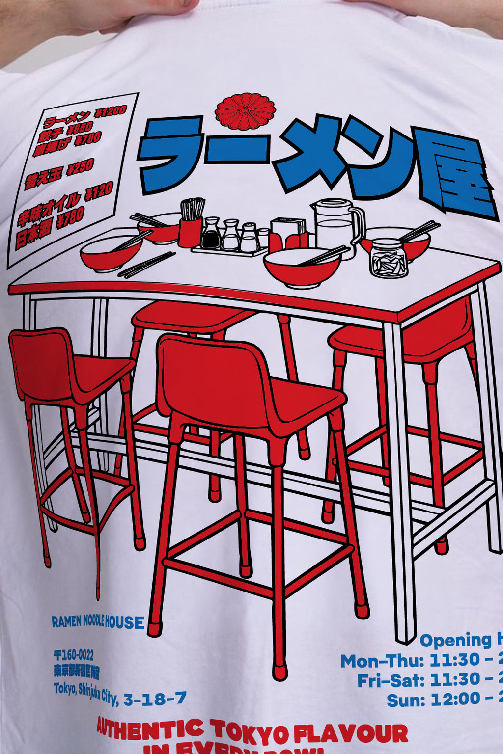 A close-up of a white graphic t-shirt featuring a red and blue ramen shop illustration with Japanese text and seating details.