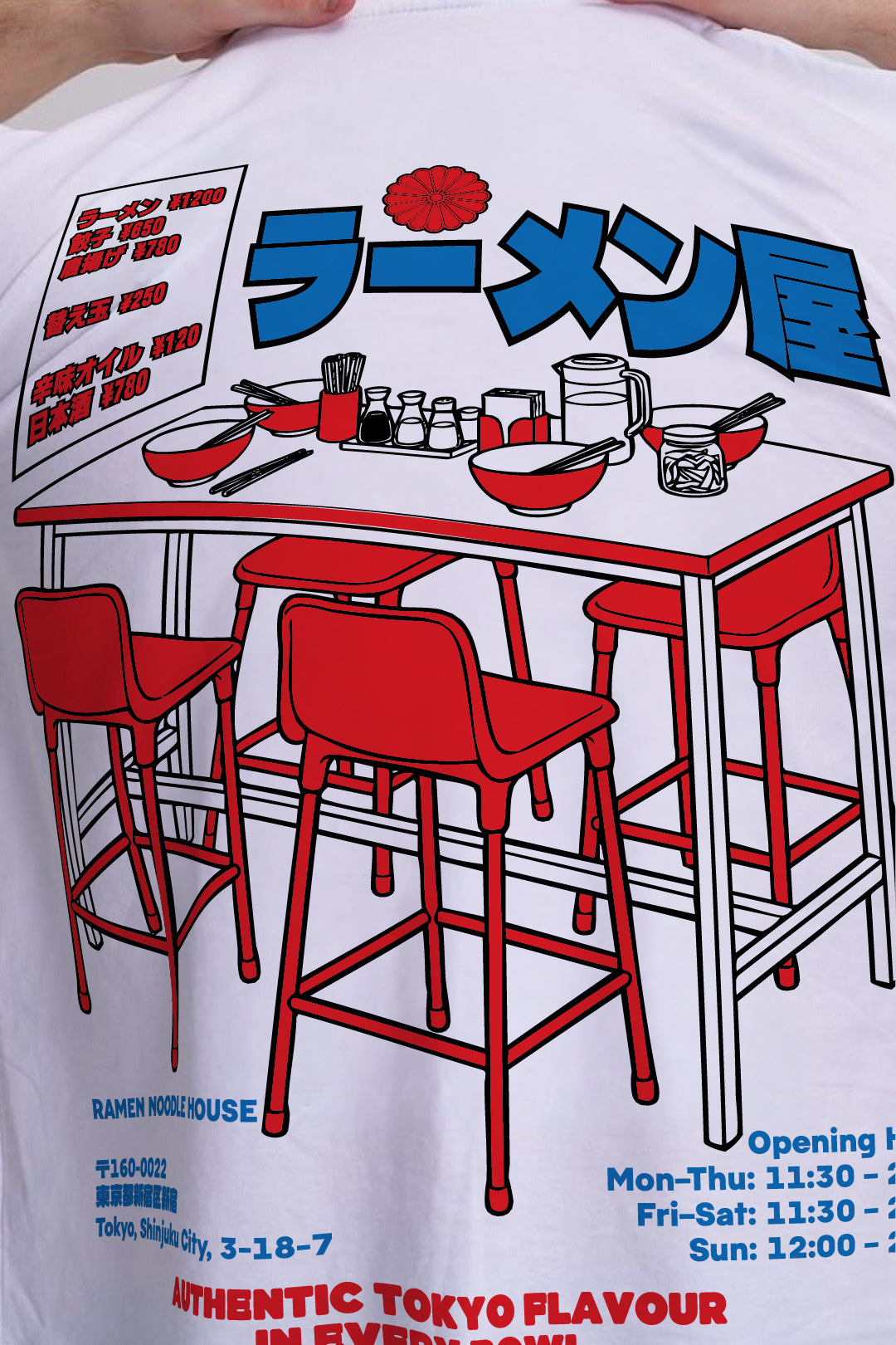 A close-up of a white graphic t-shirt featuring a red and blue ramen shop illustration with Japanese text and seating details.