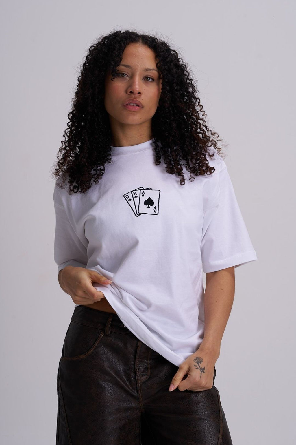 Woman wearing a white t-shirt with a black playing card design on a plain background