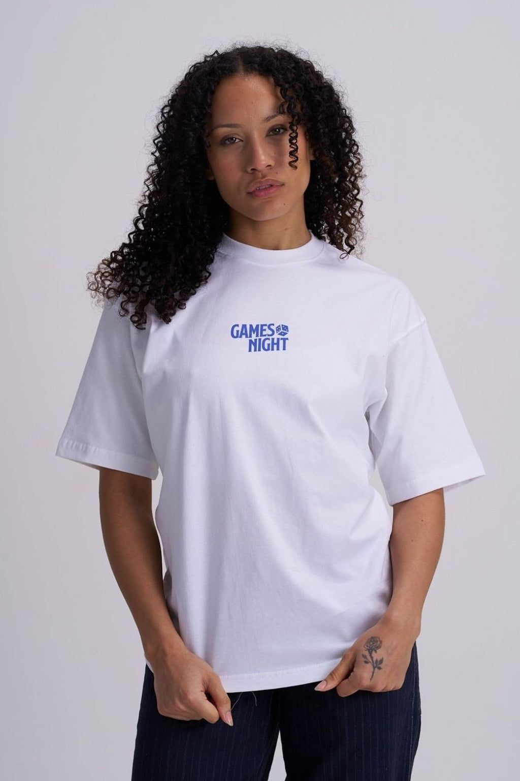 Woman wearing a white t-shirt with 'GAMES NIGHT' text on a plain background