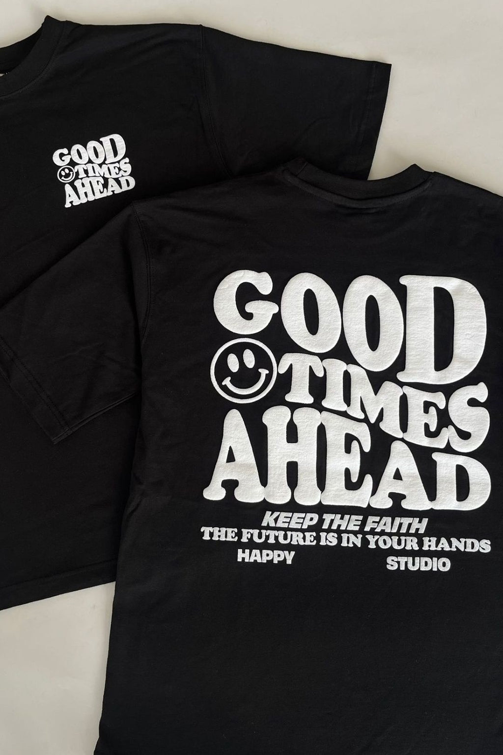 Black t-shirt with 'Good Times Ahead' text and smiley face design on a white background