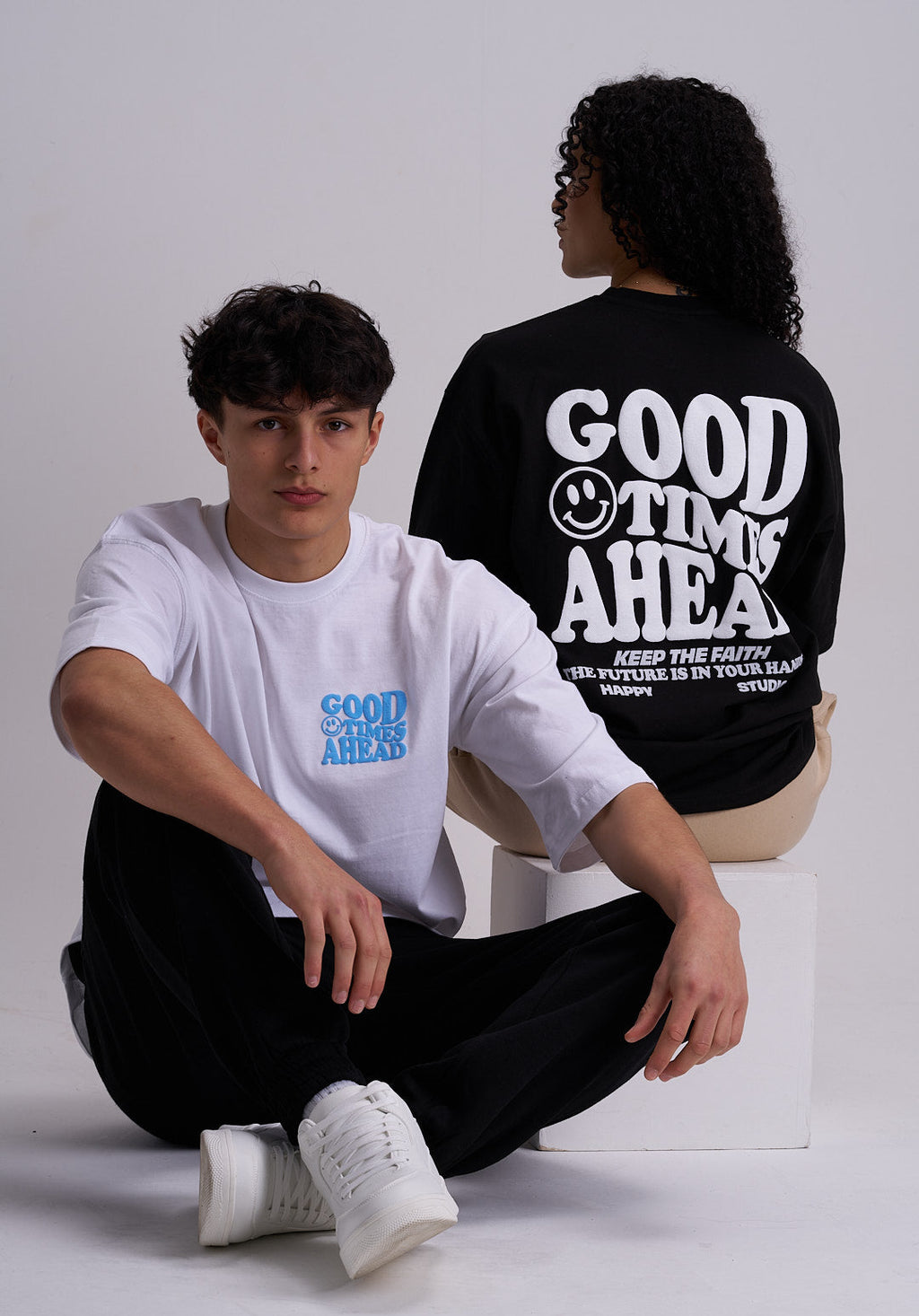 Male and a Female wearing t-shirts with "good times ahead" text and a smiley face design.