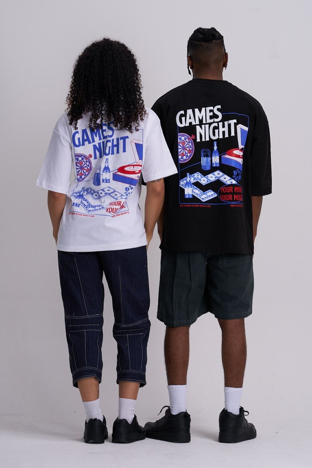 Man and woman wearing 'Games Night' themed t-shirts with graphics on a plain background