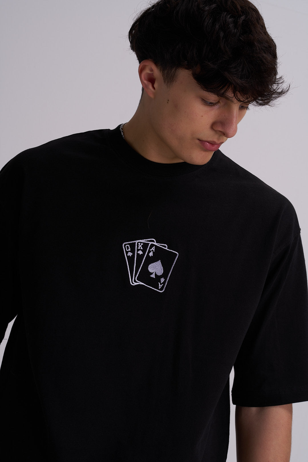 Male wearing a black t-shirt with deck of cards embroidery on the chest