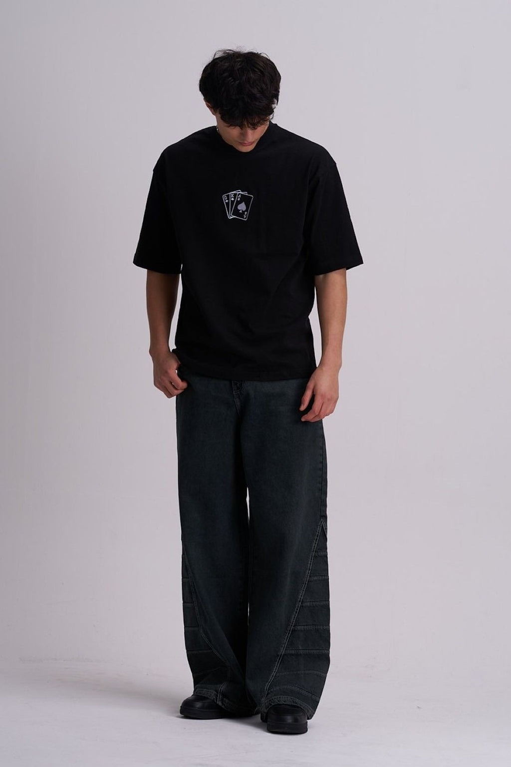 Man wearing a black t-shirt and dark pants on a white background
