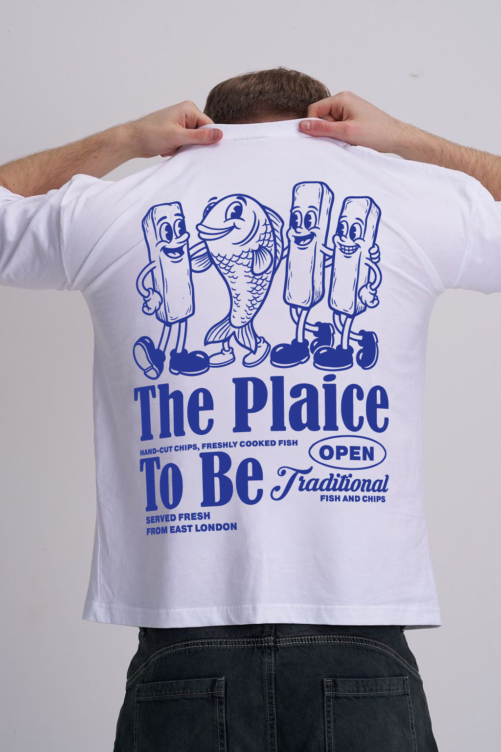 Male wearing a white t-shirt with blue graphics and The plaice to be text on the back.