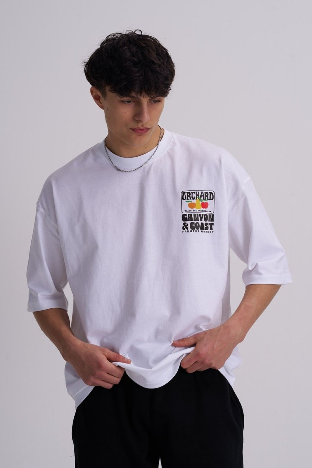 Man wearing a white t-shirt with text and graphics on a plain background