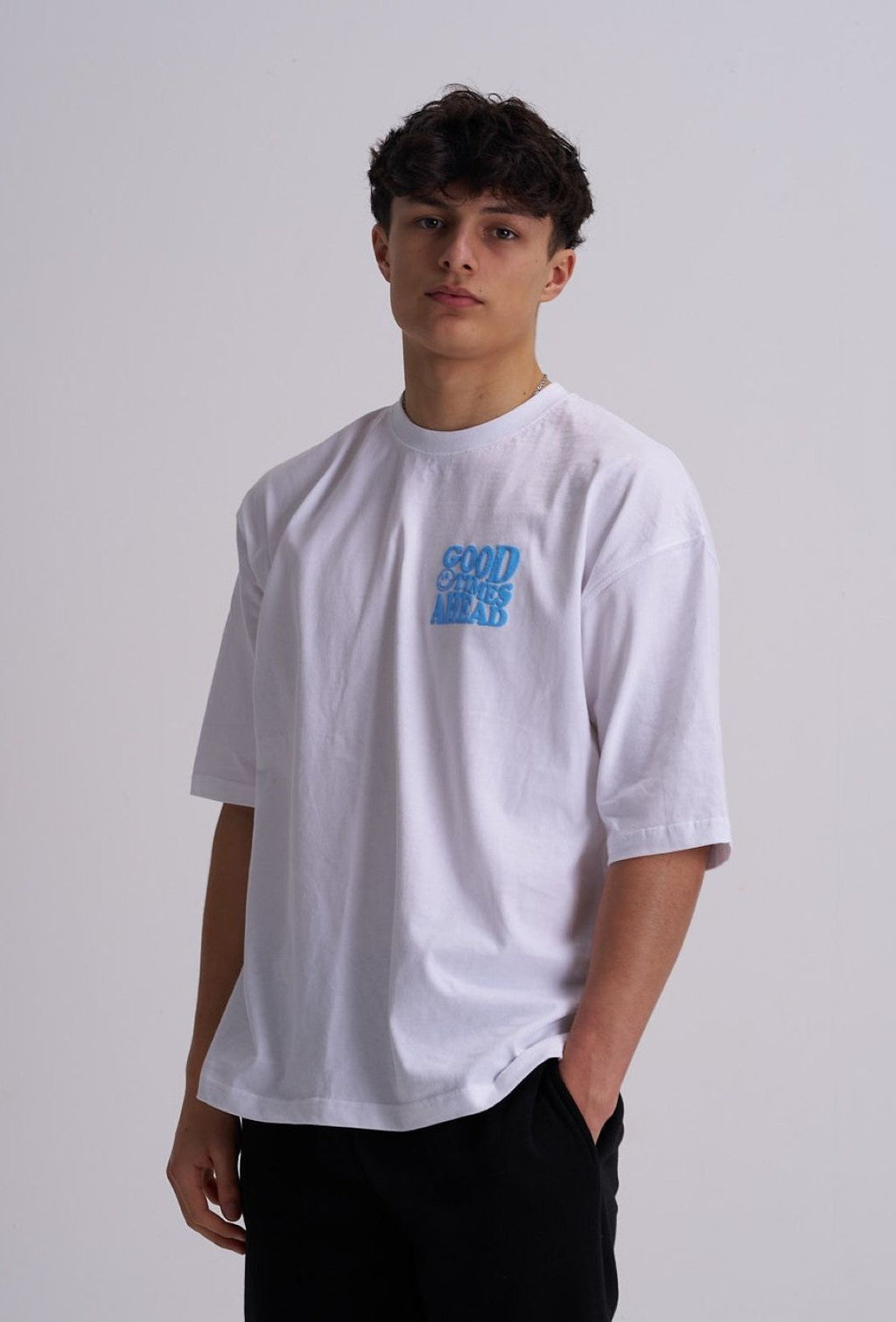 Male wearing a white t-shirt with blue text on a plain background
