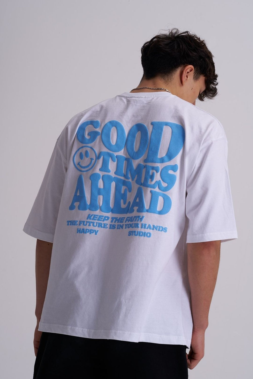 Male wearing a white t-shirt with blue text 'GOOD TIMES AHEAD' on the back against a plain background