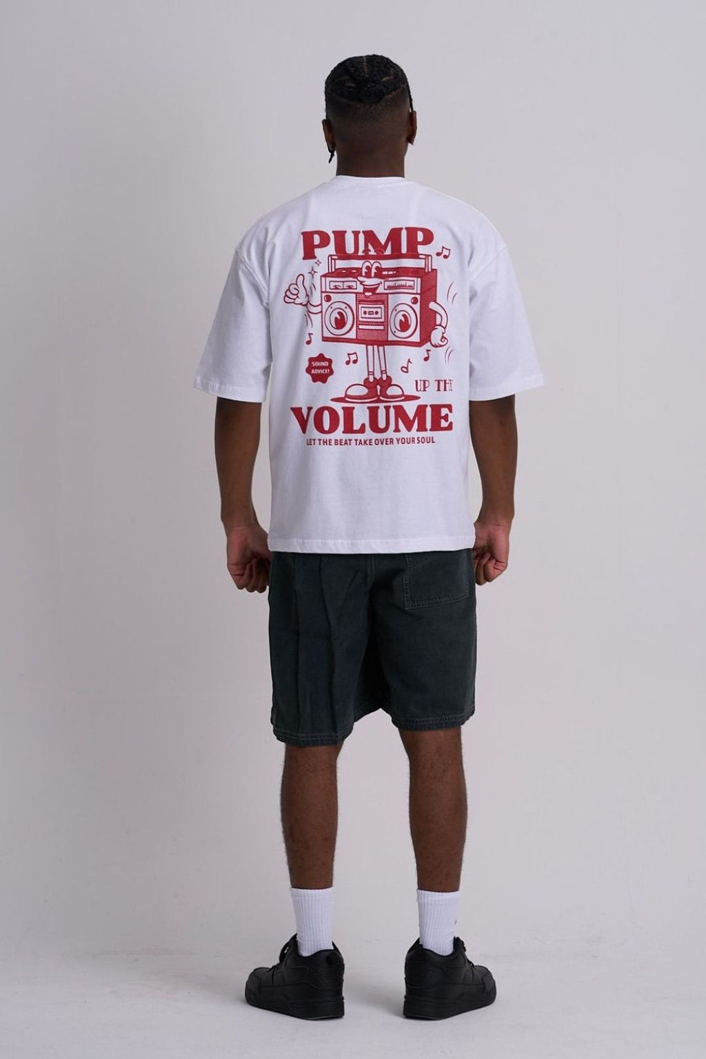 Male wearing a white t-shirt with red retro music graphics and text on the back, standing against a plain background.