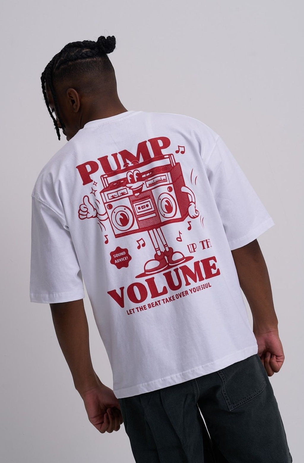 Male wearing a white t-shirt with red retro music graphic and text on the back, on a plain background