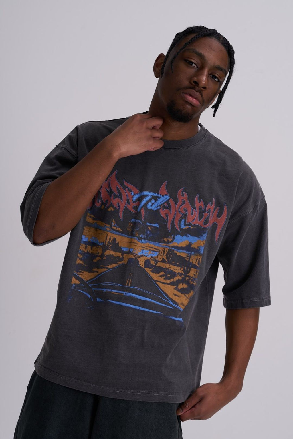 Man wearing a dark grey t-shirt with a colourful highway graphic design on a plain background