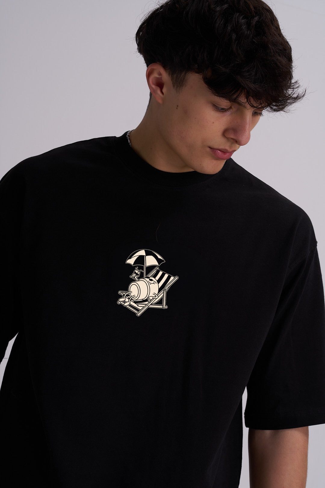 Person wearing a black t-shirt with a coffee cup on a deckchair design
