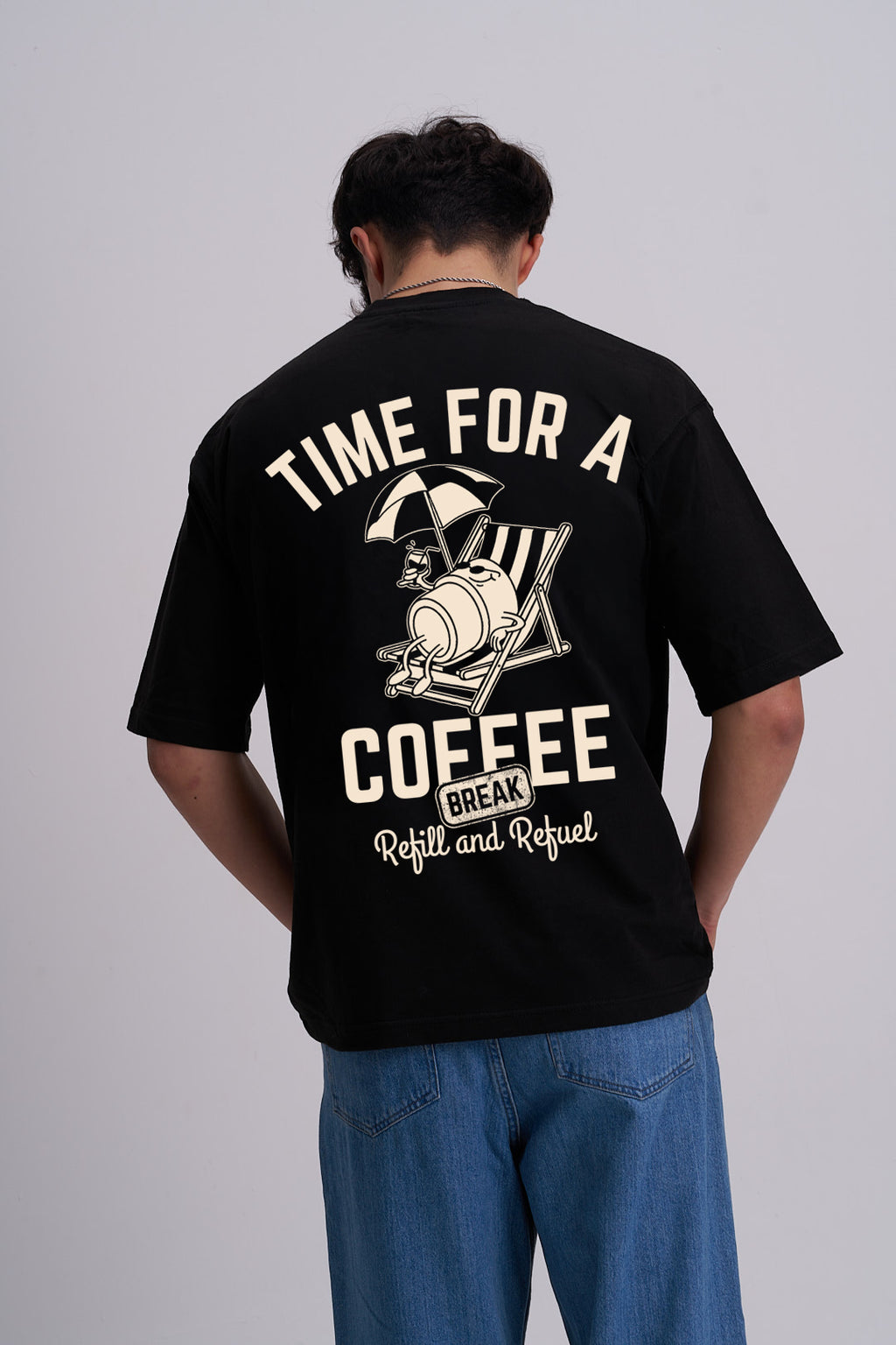 Person wearing a black t-shirt with a coffee cup on a deckchair design on the back and time for a coffee break text