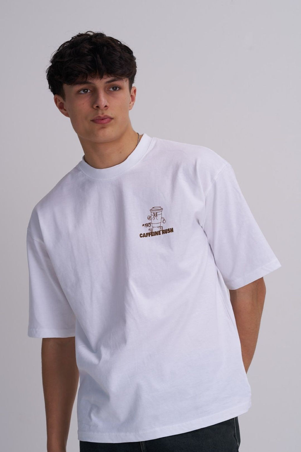 Man wearing a white t-shirt with a coffee graphic design on a plain background