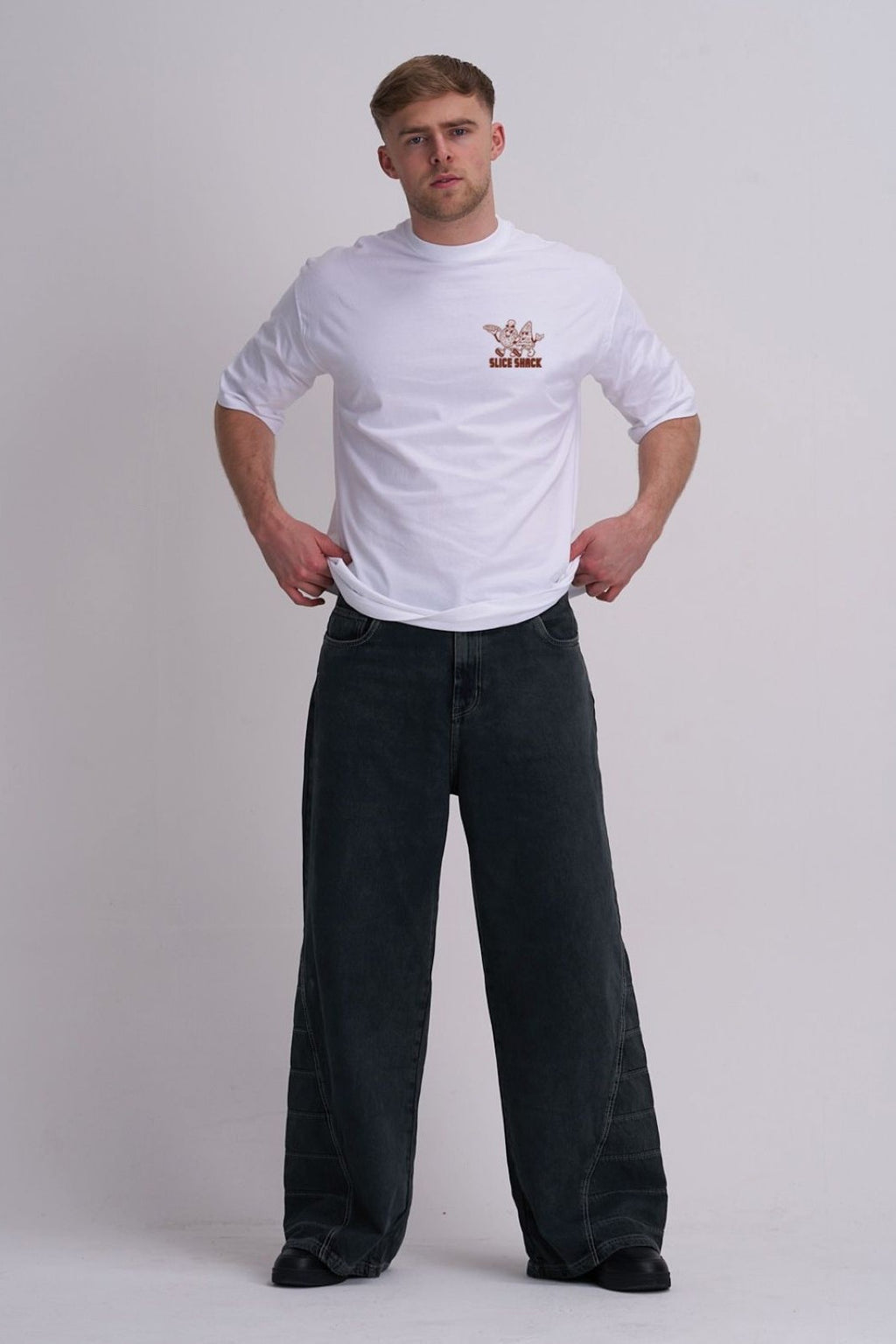 Man wearing a white t-shirt with a pizza logo and black pants on a plain background