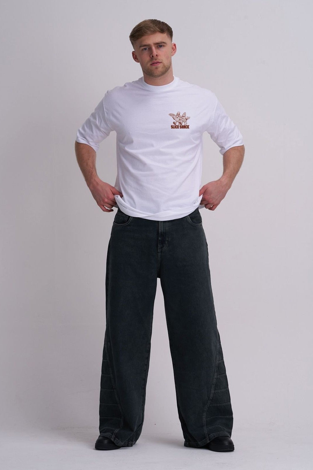 Man wearing a white t-shirt with a pizza logo and black pants on a plain background