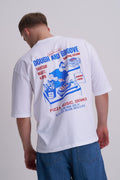 Male wearing a white t-shirt with a colourful graphic design on the back, featuring text and images of pizza and music
