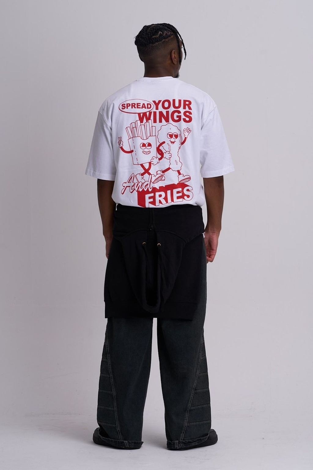 Male wearing a white t shirt with fast food graphic on the back against a plain background