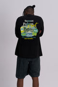A man viewed from behind wearing a black short-sleeve t-shirt with a large colourful graphic print on the back, paired with dark grey shorts, against a light grey studio background.