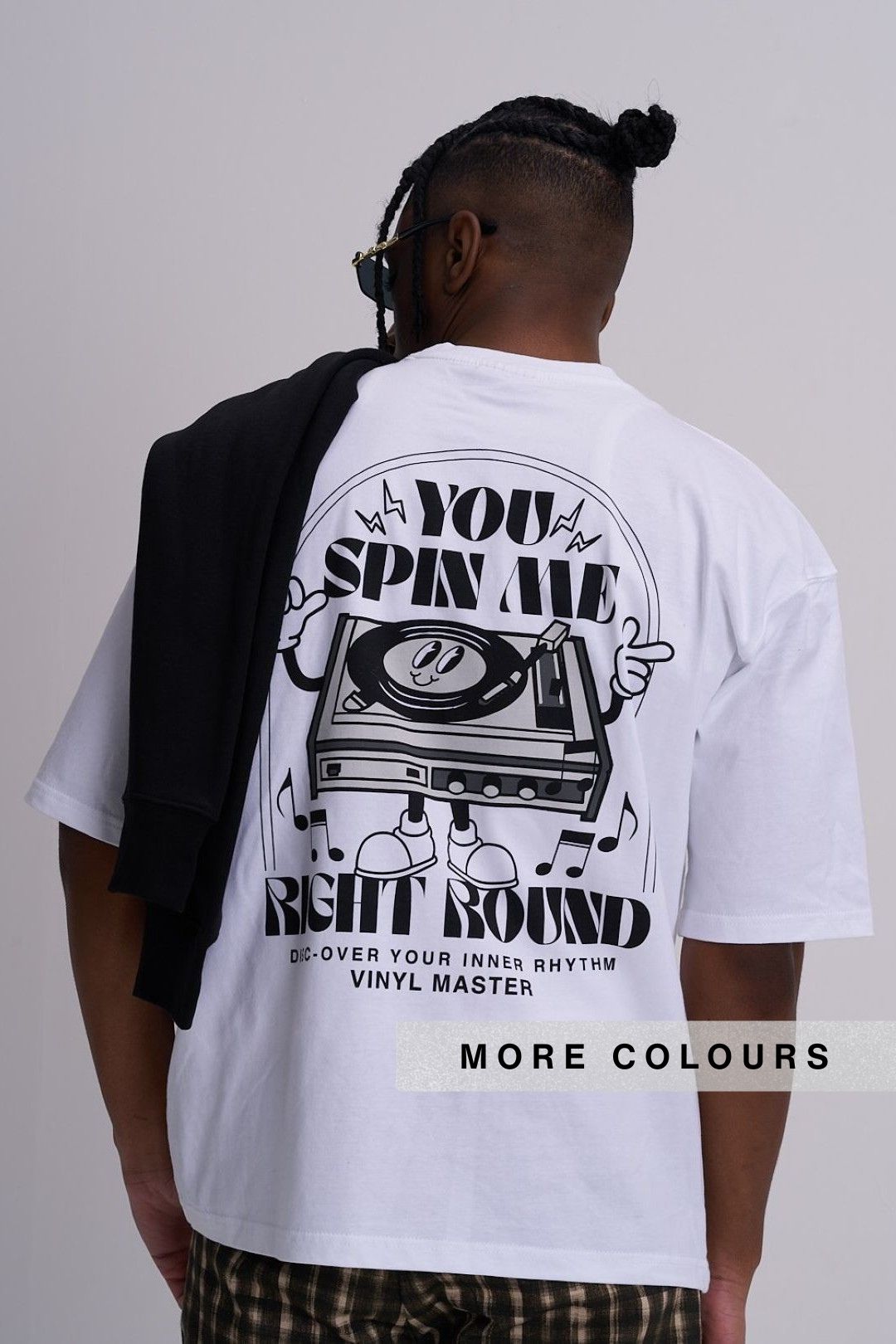 A man shown from behind wearing a white graphic t-shirt with a large black vinyl record design on the back and the text 'you spin me right round'