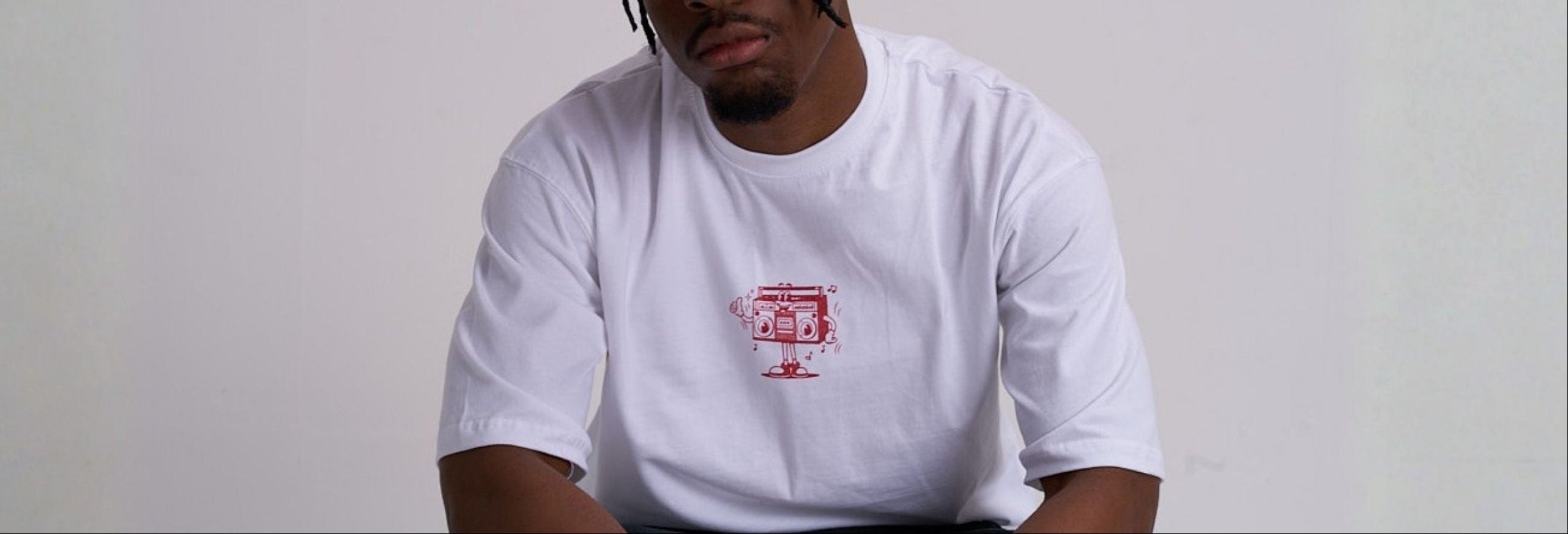 Person wearing a white t-shirt with a red retro music logo and a red cap on a plain background