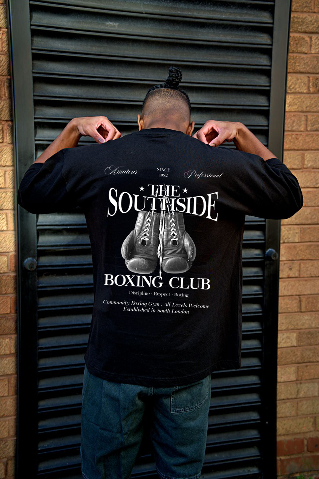 Person wearing a black t-shirt with 'The Southside Boxing Club' design, standing against a brick wall.