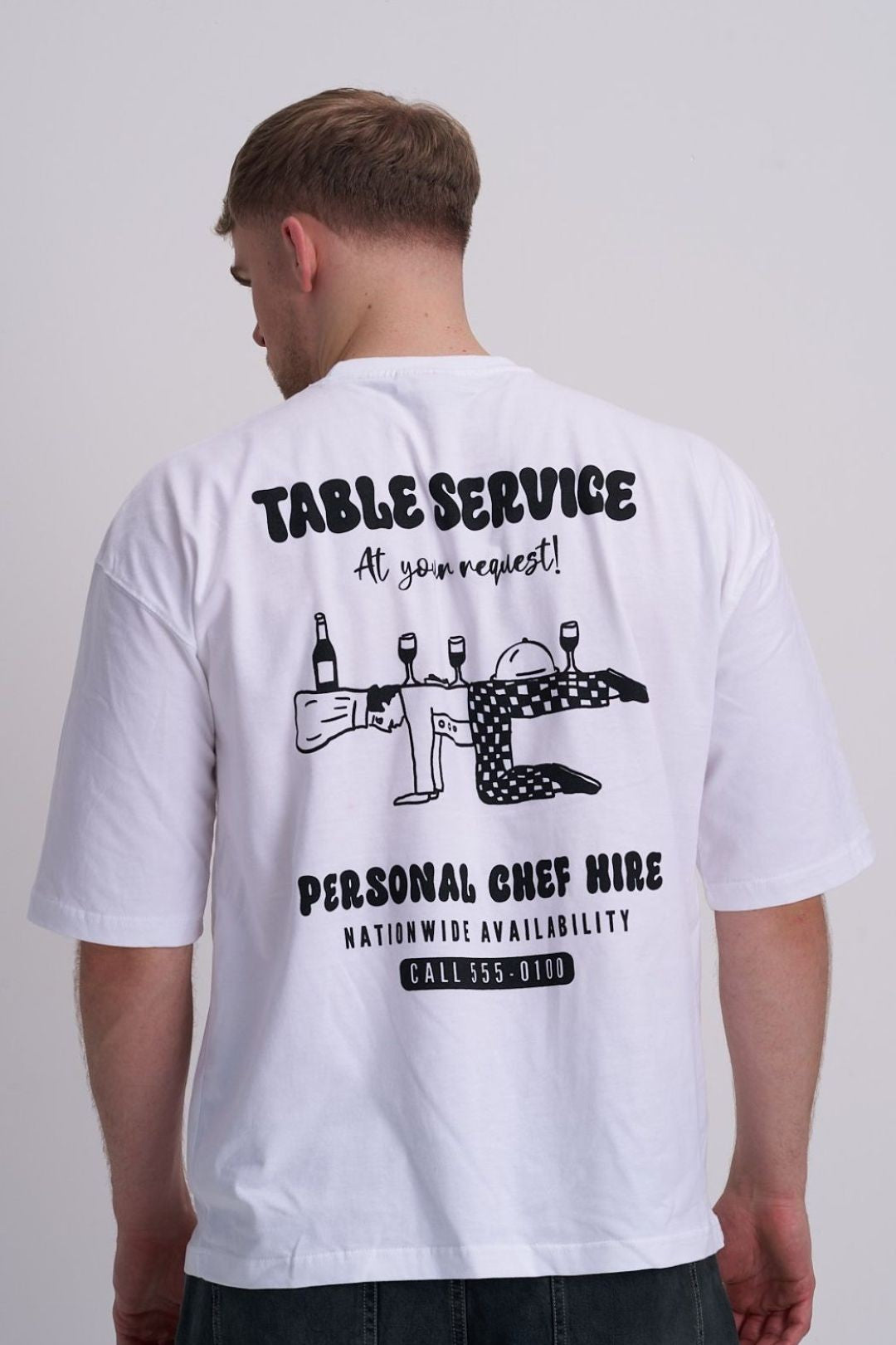 Male wearing a white t-shirt with black text "Table service - personal chef hire and chef graphic on the back.