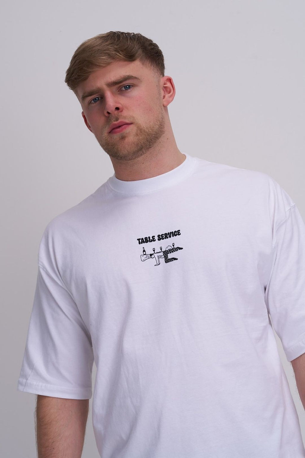 Man wearing a white t-shirt with a chef graphic design on a plain background