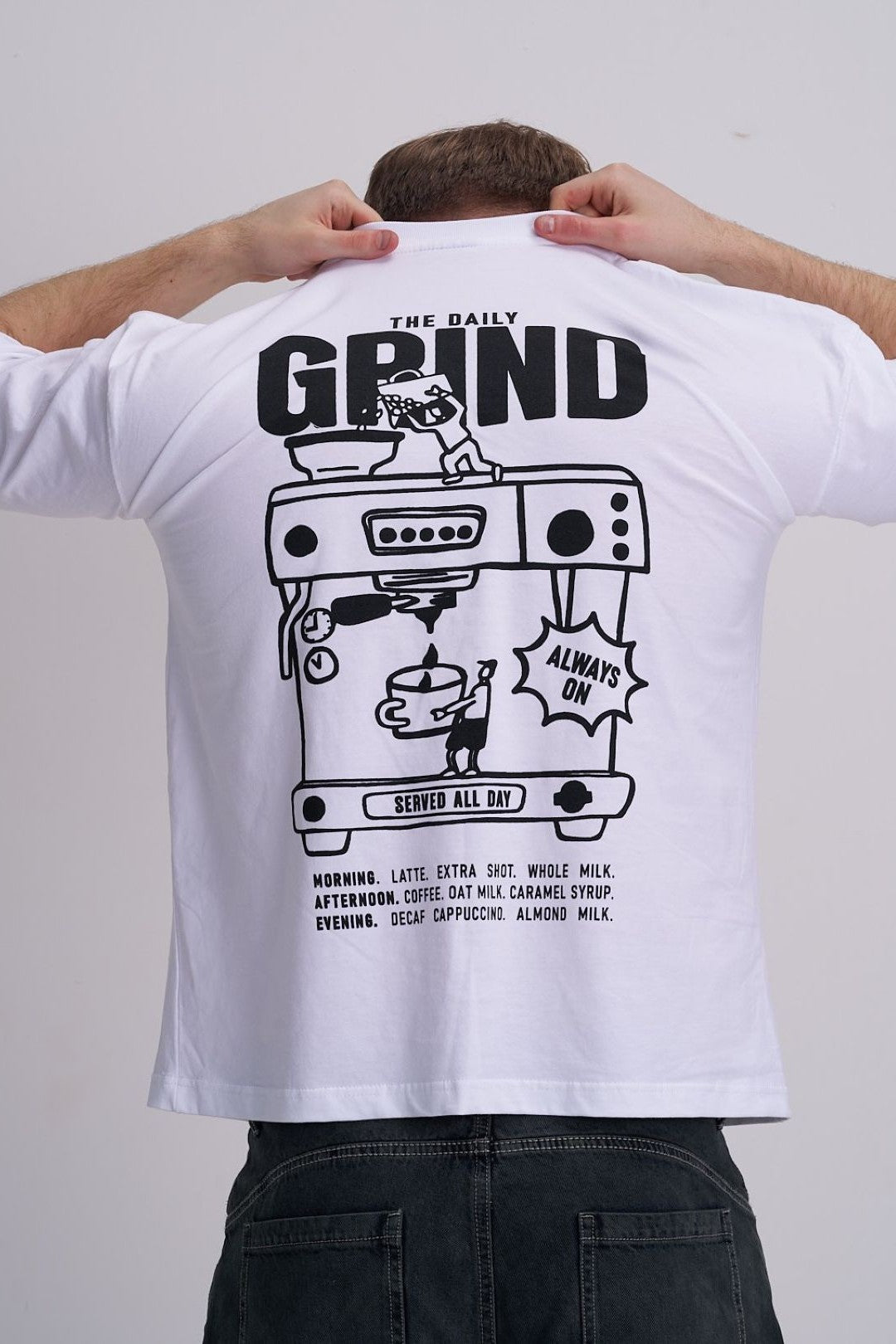 Male wearing a white t-shirt with 'The Daily Grind' coffee machine graphic design on the back.