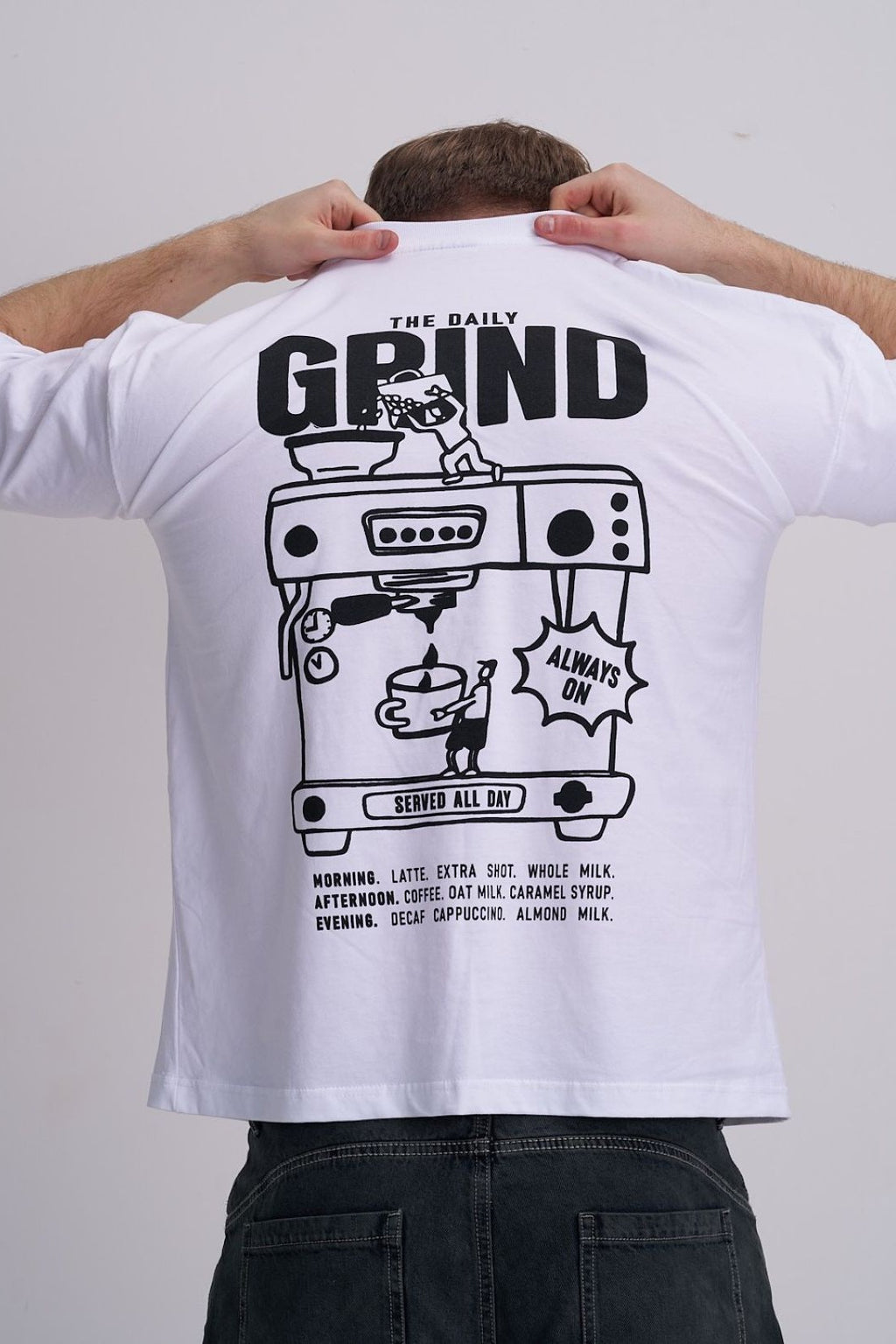 Man wearing a white t-shirt with 'The Daily Grind' graphic design on the back.