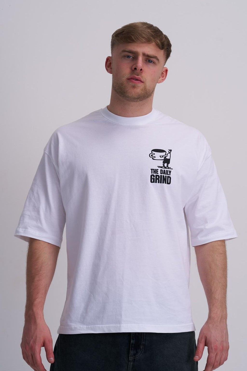 Man wearing a white t-shirt with a graphic design on a plain background