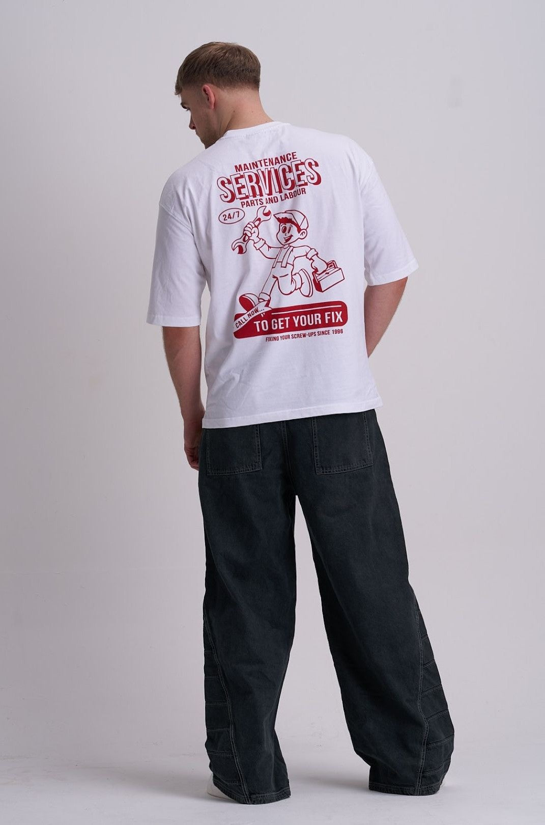 Male wearing a white t-shirt with red cartoon man holding a tool kit graphic and maintenance services text on a plain background